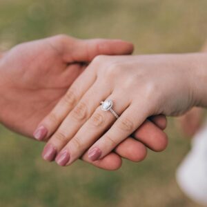 Romantic gesture of couple holding hands, showcasing a diamond engagement ring.