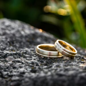 selective focus photography of two gold-colored rings on black stone during daytime